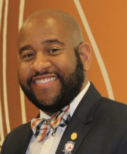 Man smiling in a suit and bow tie.