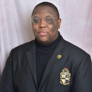 Man wearing glasses and crest blazer