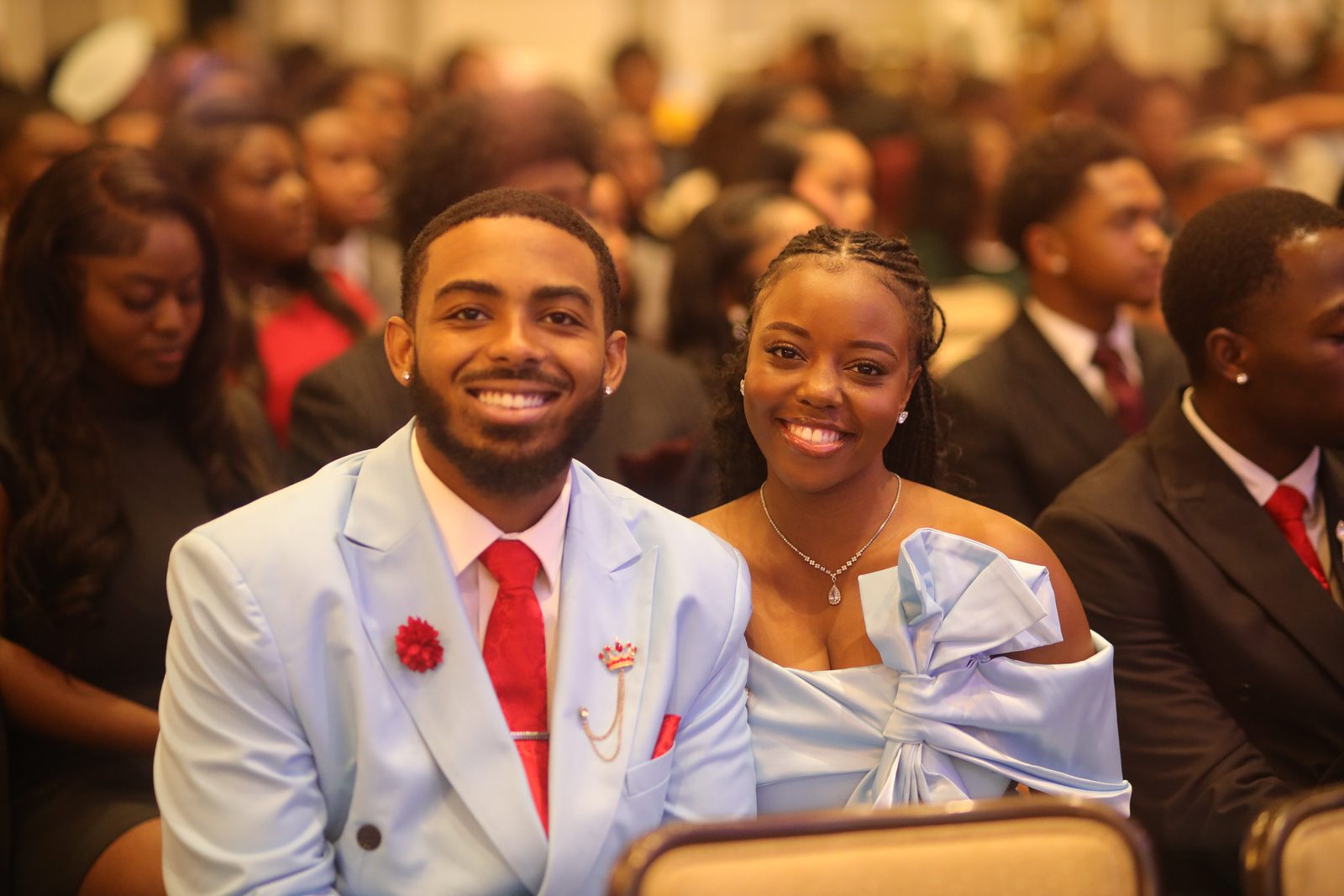 Two smiling individuals dressed formally at an event.
