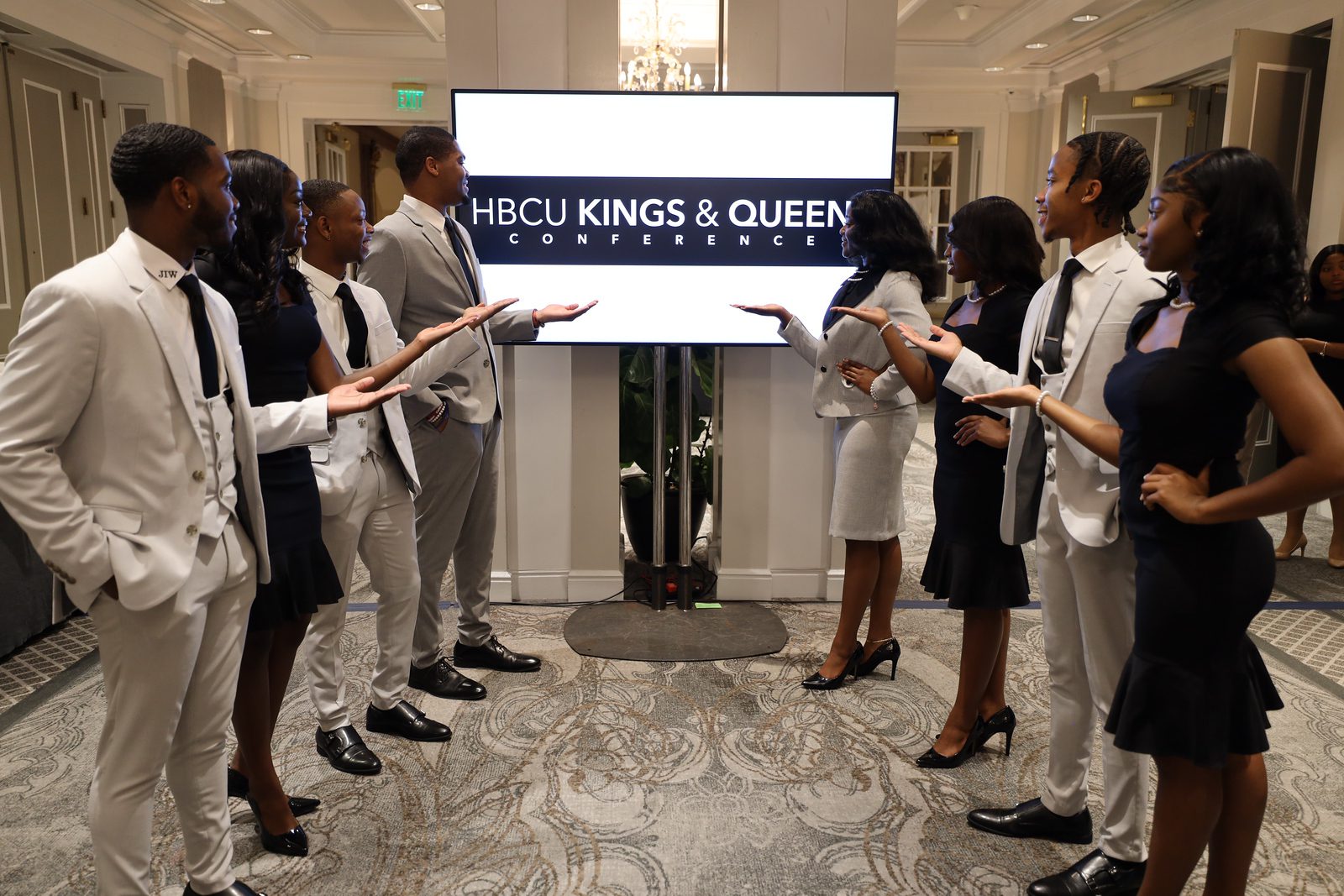 Two groups dressed formally, holding papers, facing each other in a room.