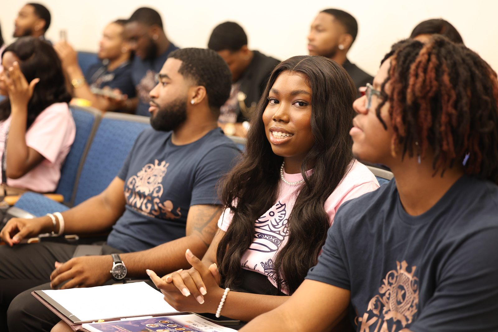 Young adults attentively listening in a classroom or seminar setting.