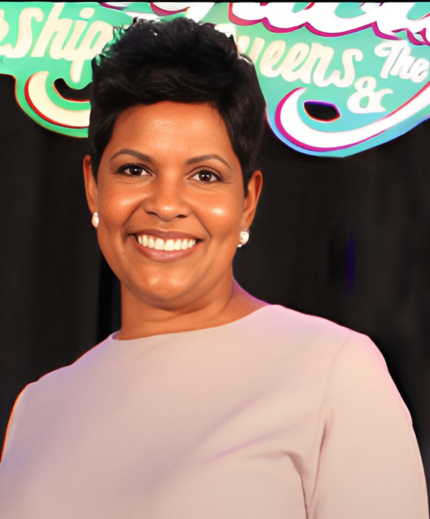 Smiling woman with short hair in a light pink top.
