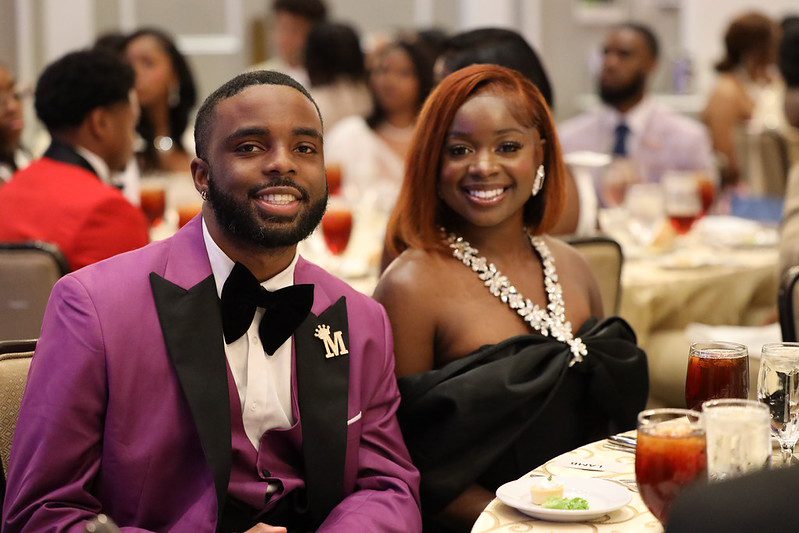 A well-dressed couple smiling at a formal event.