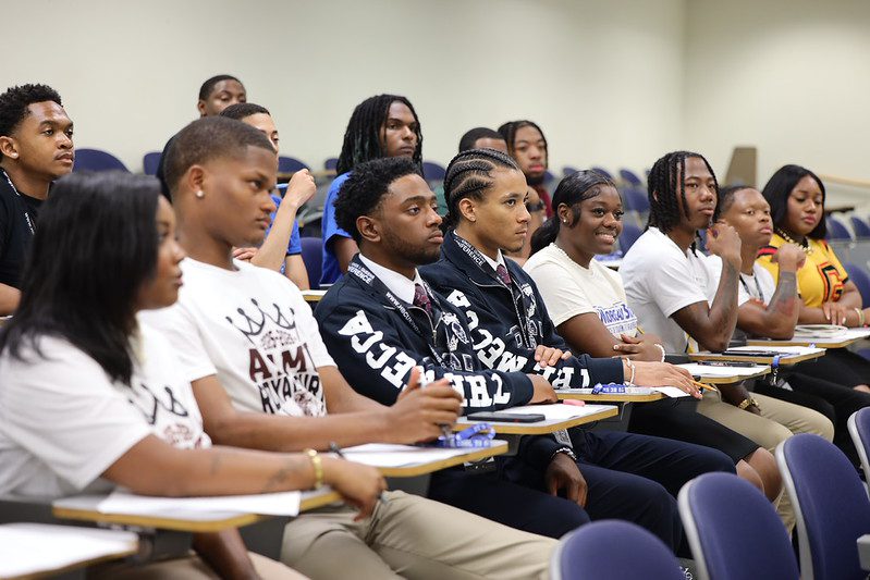 Young adults attentively listening in a classroom setting.